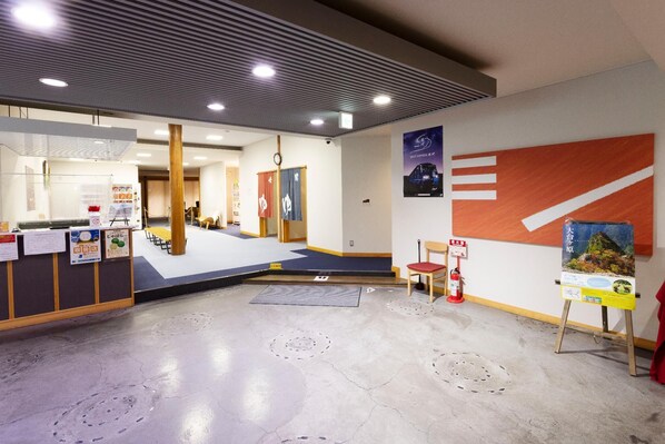 Un hall d’hôtel avec un comptoir d’accueil, un escalier et un mur orné d’affiches.