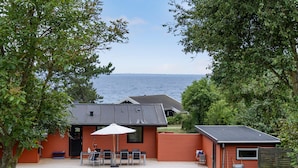 A cabin with a patio, a table with chairs, and a view of the sea. - 3 bedroom cozy home in Martofte (Martofte)