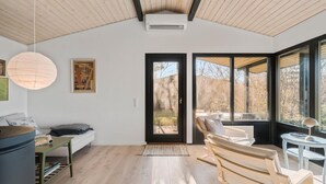 A modern interior with a wooden ceiling, a large window, and a door leading outside. - 3 bedroom cozy home in Martofte (Martofte)