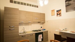 Una cocina moderna con armarios de madera, horno empotrado y comedor con mesa lista para dos personas.
