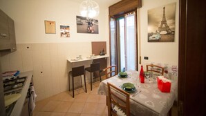 Comedor con una mesa lista para cuatro, área de cocina con estufa y ventana con vista a la Torre Eiffel.