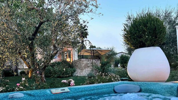 Un jacuzzi con pared de piedra y un objeto esférico blanco grande cerca.