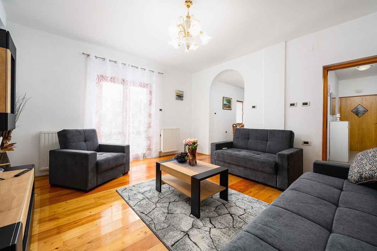 A living room with two grey sofas, a wooden coffee table, and a patterned rug.