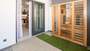Un apartamento moderno con una puerta corredera de vidrio que da a la cocina, un armario de madera con varios compartimentos y una pequeña alfombra verde.