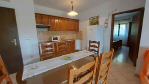 A compact kitchen with wooden cabinets, a microwave, and a refrigerator. - Holiday apartment with air conditioning in a beautiful setting (Funtana)