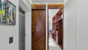 Un corridoio con una porta in legno, un quadro appeso al muro e un armadio con scaffali.