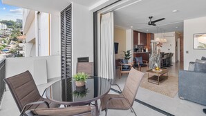 Un appartamento moderno con un balcone, un'area pranzo con tavolo in vetro e un soggiorno con divano e tavolino.