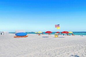 Una playa con sombrillas, sillas de playa y una torre de salvavidas.