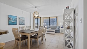 A dining area with a wooden table and chairs, a chandelier, and two paintings on the wall.