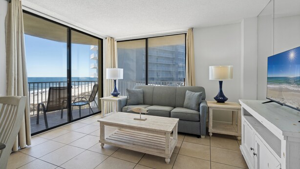 A modern hotel room with a balcony, a sofa, a coffee table, and a TV.