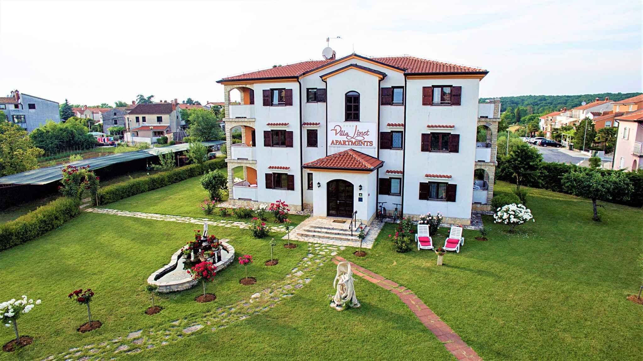 Villa Linct Apartments with a central entrance, a garden with a fountain, and a view of the surrounding neighborhood.