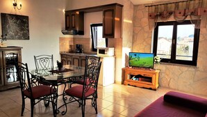 A dining area with a glass table and chairs, a kitchen with wooden cabinets, a TV on a wooden stand, and a window with a view. - Holiday apartment in a beautiful setting, with air conditioning (Funtana)