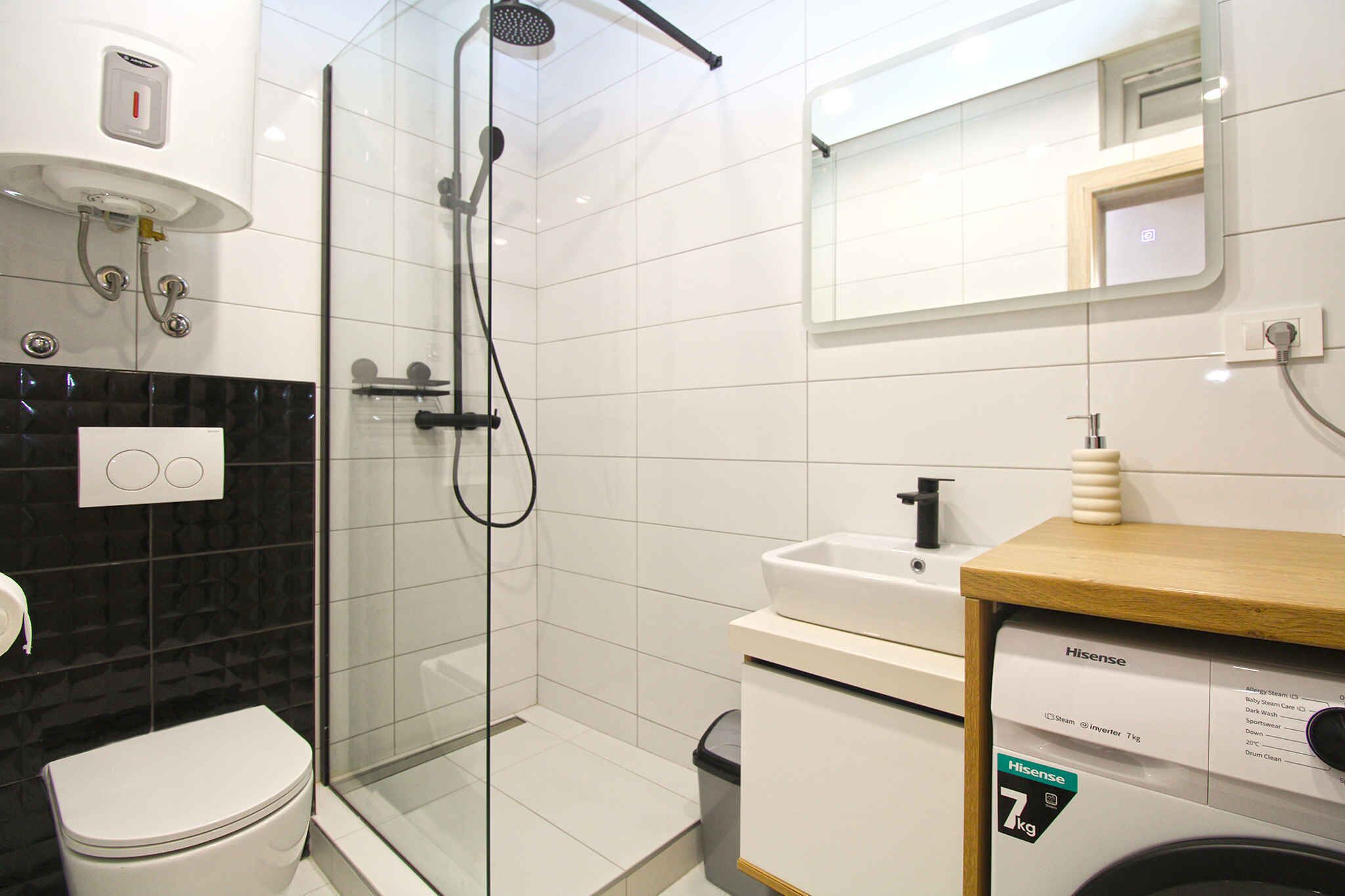 Une salle de bain moderne avec une douche à parois de verre, des toilettes blanches, un lavabo et un lave-linge.