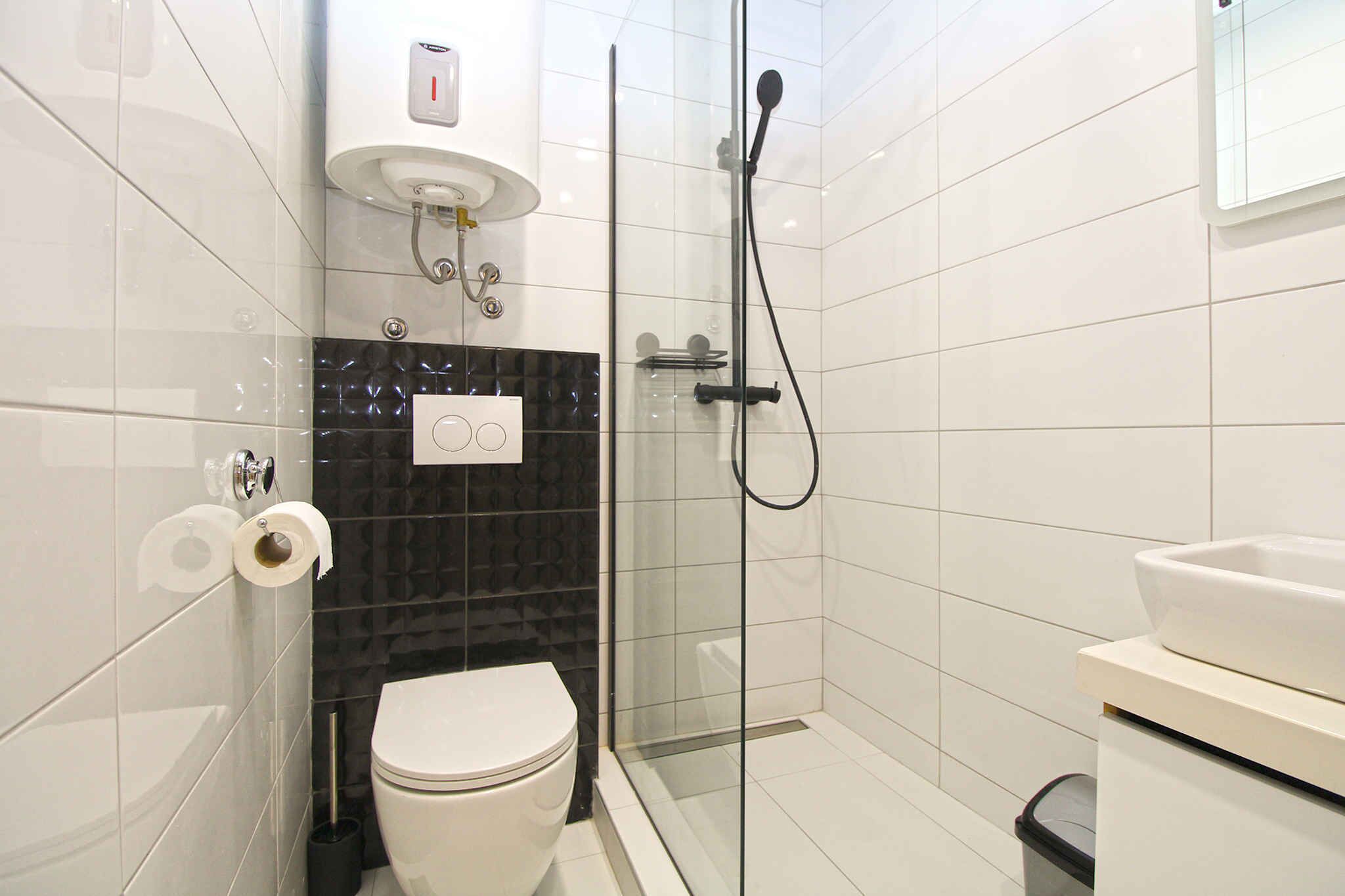 Een moderne badkamer met toilet, een douchecabine en een wastafel.
