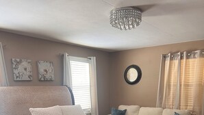 Una camera da letto con un letto grande, una testiera in legno, un divanetto e un lampadario.