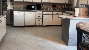 Cucina con mobili bianchi, isola centrale e forno a microonde.