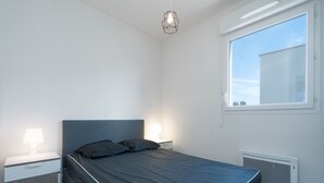 A modern bedroom with a bed, bedside tables, and a window.