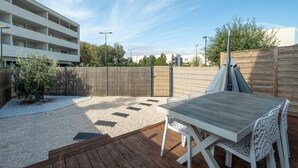A patio with a wooden deck, a table, and chairs.