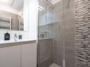 Enjoy a refreshing shower in this sleek bathroom with a glass-enclosed shower area and modern amenities.