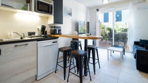 A modern kitchen with a microwave, dishwasher, and bar stools. - Beautiful duplex villa for 5 pers, air-conditioned (Sérignan)