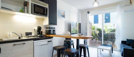 A modern kitchen with a microwave, dishwasher, and bar stools.