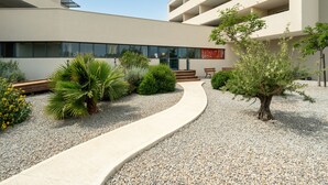Un bâtiment moderne doté d’un chemin sinueux, de bancs et d’une variété de plantes.