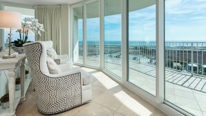 Ein modernes Wohnzimmer mit großem Balkon, weißen Möbeln und Blick auf die Stadt.