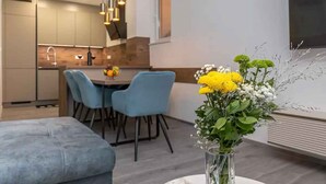 Una cucina moderna con zona pranzo, che include un tavolo con sedie, un vaso con fiori e un'ampia finestra.