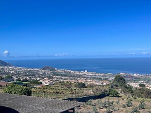 A coastal town with a view of the sea, buildings, and a hill.