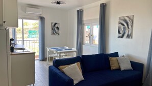 A living area with a blue sofa, a dining table with chairs, a kitchen area, and a balcony with a view. - Sea View Apt4 Finca TenDays Orotava with Sea View, Wi-Fi and Air Conditioning (La Orotava)