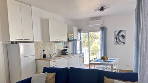 A modern kitchen with white cabinets, a refrigerator, and a dining area with a table and chairs. - Sea View Apt4 Finca TenDays Orotava with Sea View, Wi-Fi and Air Conditioning (La Orotava)
