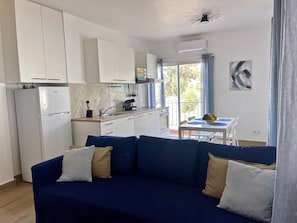 Une cuisine moderne avec des meubles blancs, un réfrigérateur et un coin repas comprenant une table et des chaises.