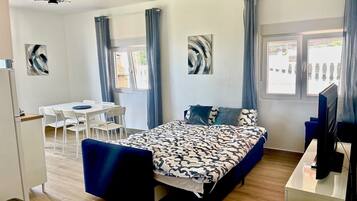 Una habitación de hotel con cama, escritorio, silla, televisión y ventana.