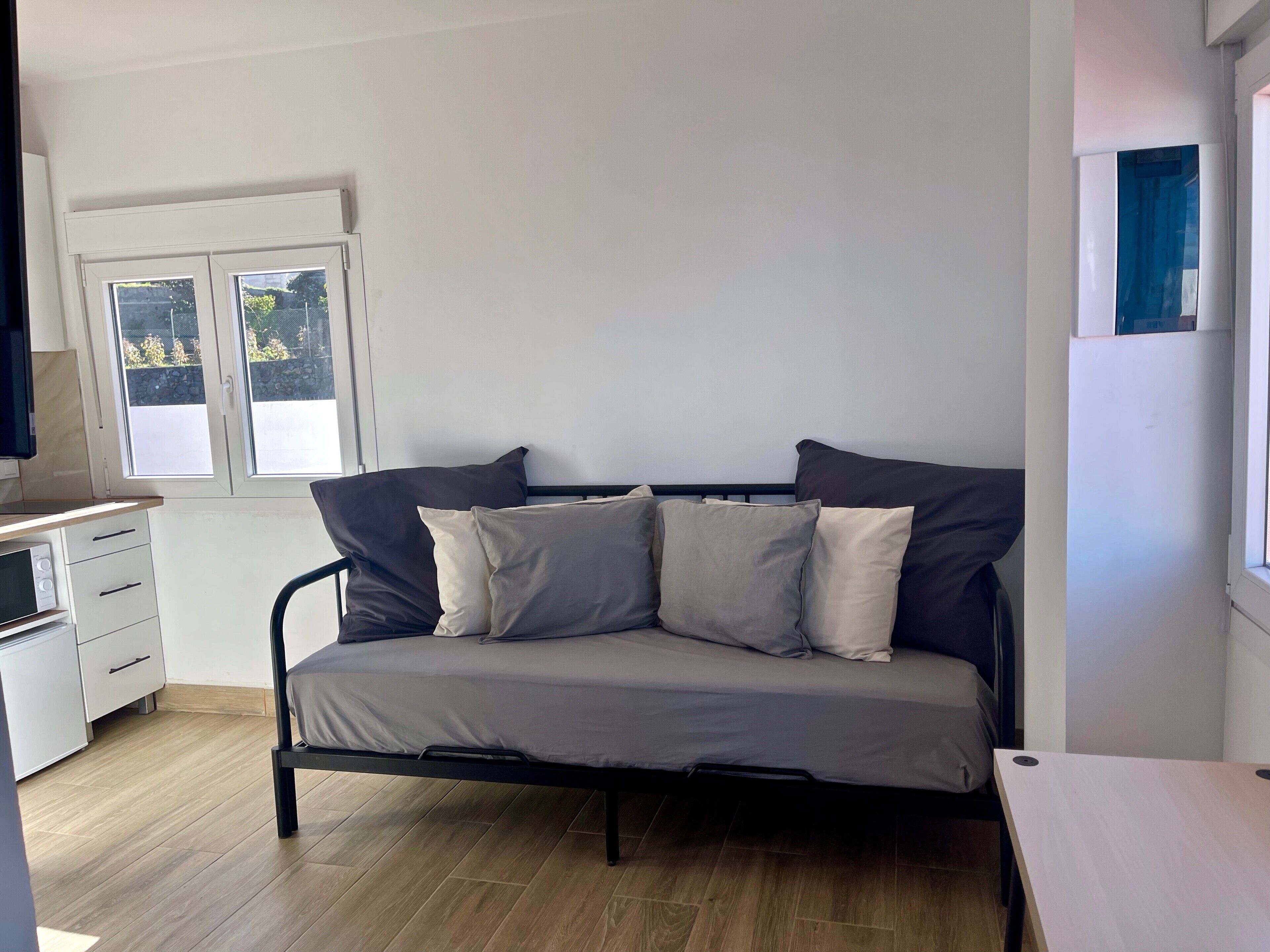 Een kamer met een bed, een bureau, een magnetron en een raam.