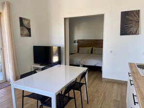 Une chambre d’hôtel avec un lit, une télévision, une table à manger et des chaises.