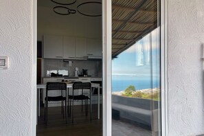 Een moderne keuken met witte kasten en een eethoek met zwarte stoelen.