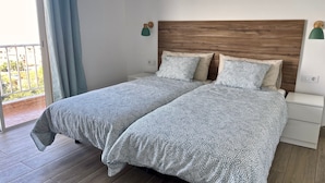 A double bed with patterned bedding, a wooden headboard, bedside tables, and a view of the outdoors through a window. - Sea View Apt3 Finca TenDays Orotava with Wi-Fi and Air Conditioning (La Orotava)