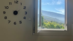 A wall clock with a view of a landscape through a window. - Sea View Apt3 Finca TenDays Orotava with Wi-Fi and Air Conditioning (La Orotava)
