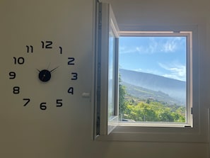Un reloj de pared con vista a un paisaje a través de una ventana.