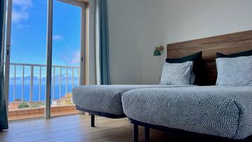 Un dormitorio con un amplio ventanal corredera que da a un balcón con vistas al mar.