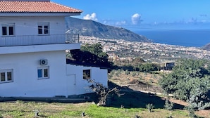 A white building with a red-tiled roof, a balcony, and a view of a coastal town and mountains. - Sea View Apt3 Finca TenDays Orotava with Wi-Fi and Air Conditioning (La Orotava)