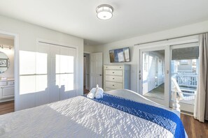 Relax in a spacious room with a large bed, white drawers, and a table with a lamp.
