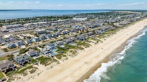Luchtbeeld van een kustgebied met woningen, een strand en een jachthaven.