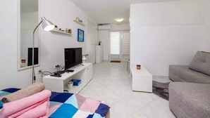 Una habitación moderna y bien iluminada con una cama, un televisor, un escritorio y un sofá.