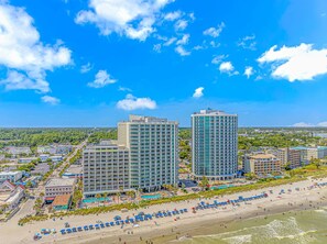 A coastal hotel with multiple high-rise buildings, a beachfront, and a pool area.