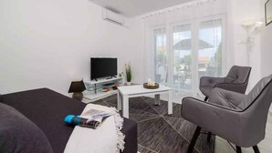 Una sala de estar moderna con una televisión de pantalla plana, un sofá, una mesa de centro y un sillón gris.