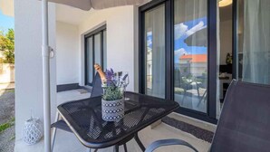 Un espacio al aire libre con mesa, sillas y un florero decorativo.