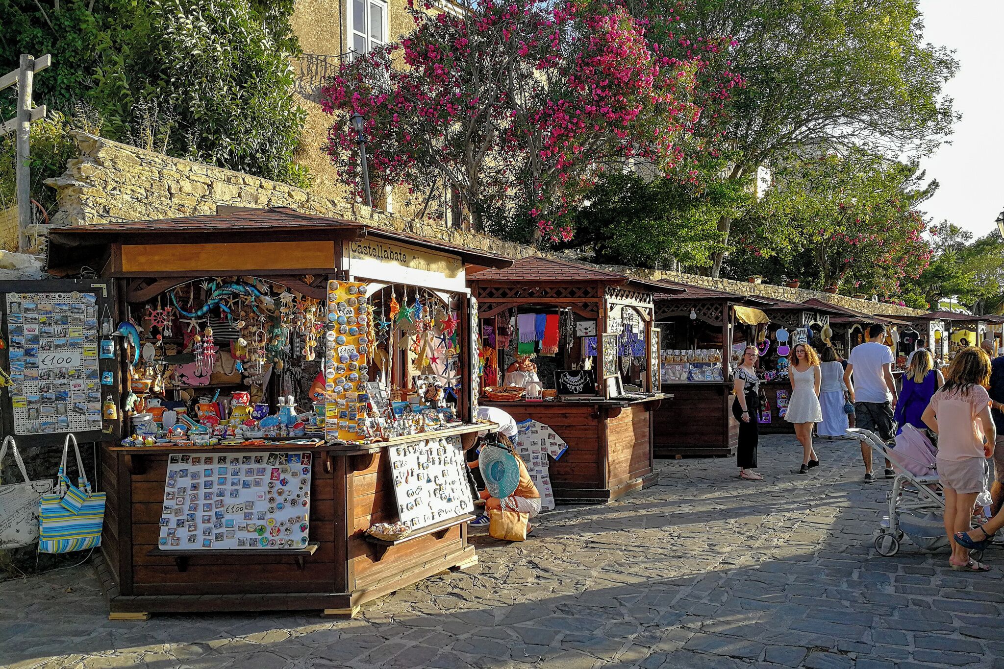 Un marché de rue avec des étals en bois où sont vendus divers articles.
