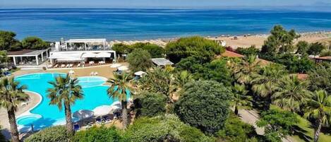 Un resort con una amplia piscina, exuberante vegetación y vista al océano.