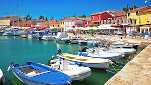 A marina with boats docked, a stone quay, and colorful buildings in the background. - Holiday home with air conditioning and pool (Novigrad)